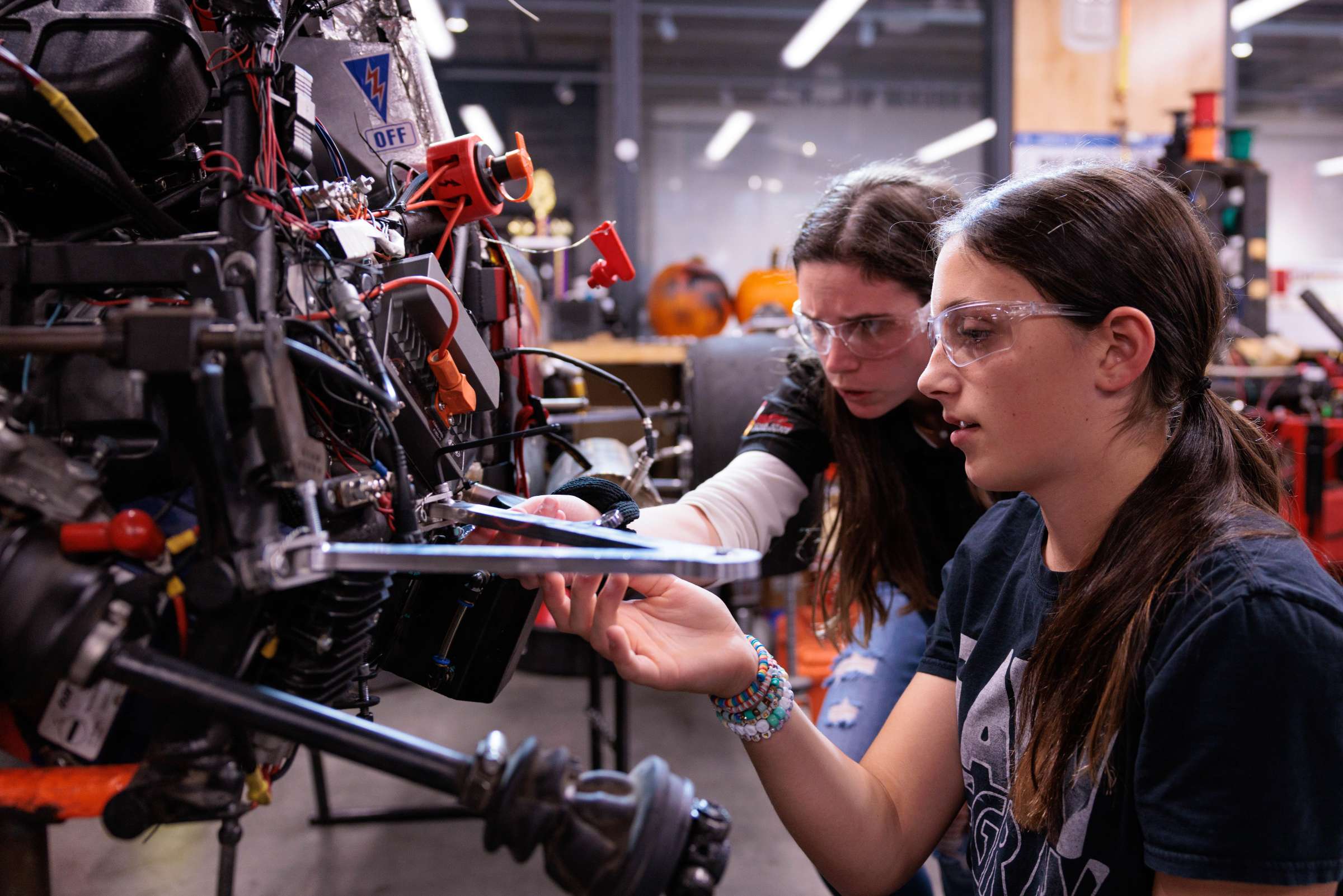 Two teenage youth program participants engaging with robotic equipment